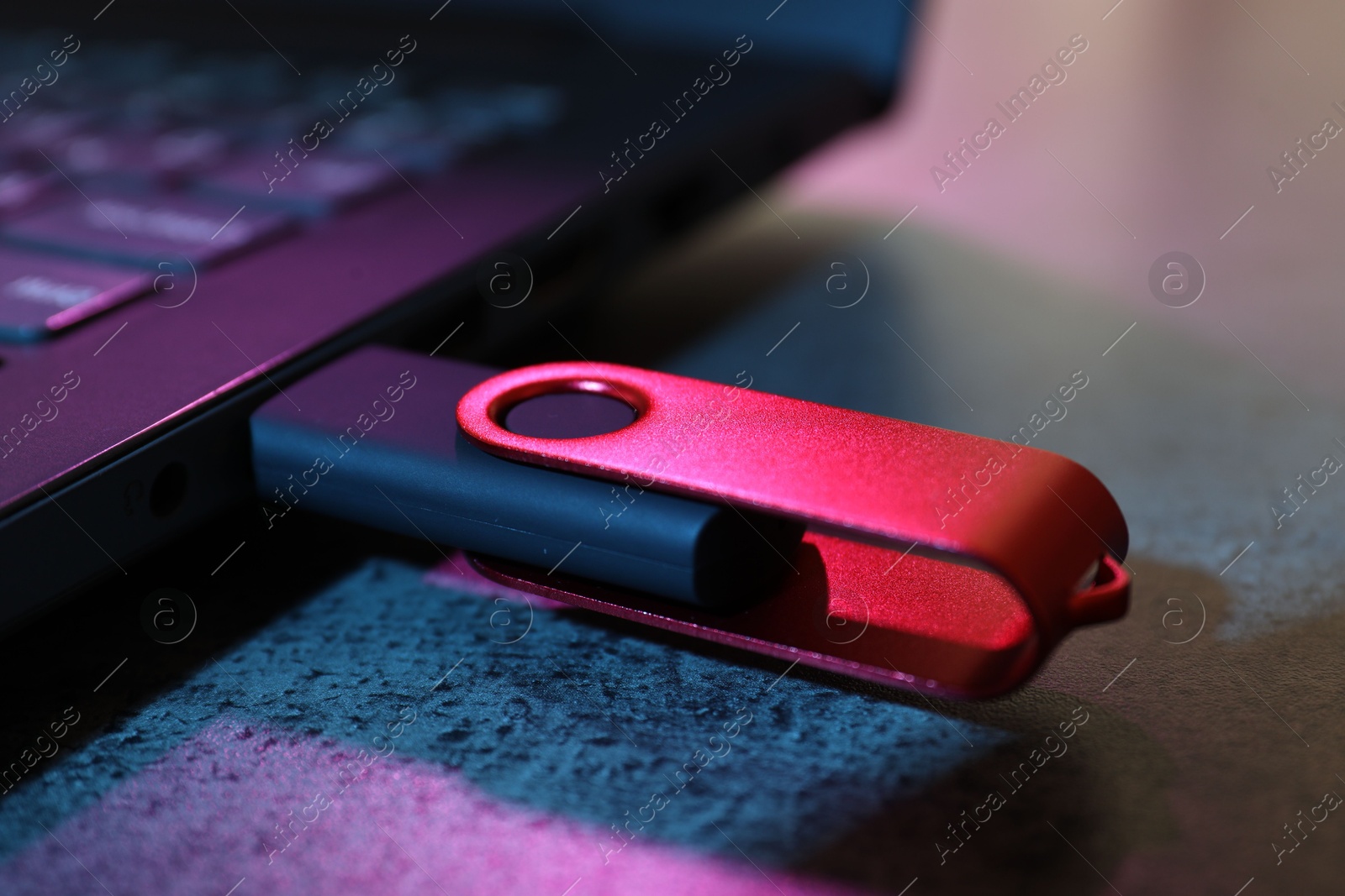 USB flash drive connected to laptop on dark grey table, closeup Photo of USB flash drive connected to laptop on dark grey table, closeup