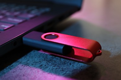 Photo of USB flash drive connected to laptop on dark grey table, closeup