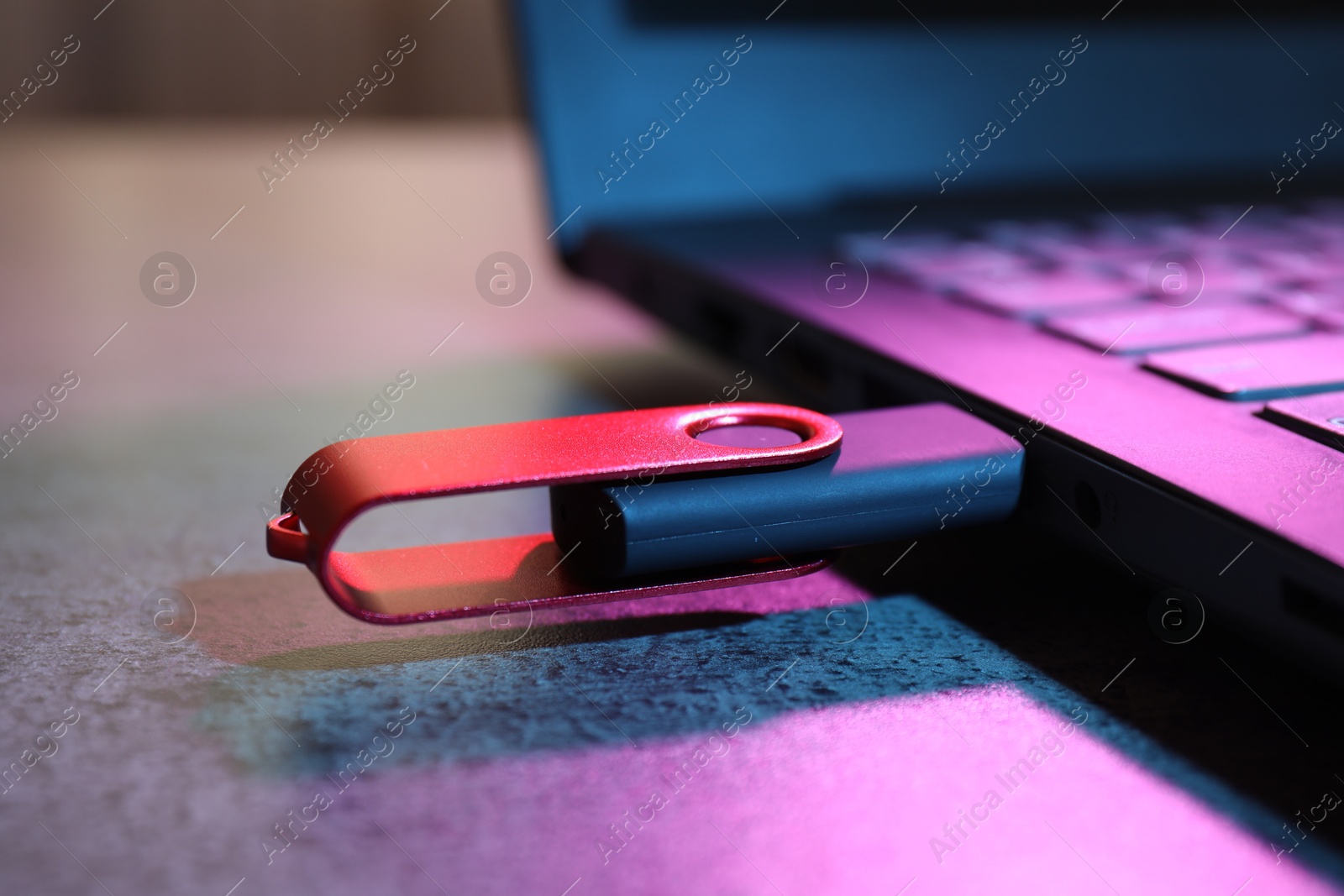 USB flash drive connected to laptop on dark grey table, closeup Photo of USB flash drive connected to laptop on dark grey table, closeup