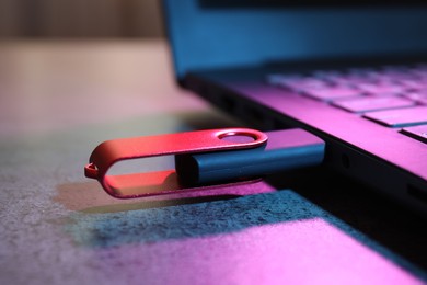 Photo of USB flash drive connected to laptop on dark grey table, closeup