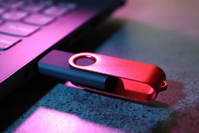 Photo of USB flash drive connected to laptop on dark grey table, closeup
