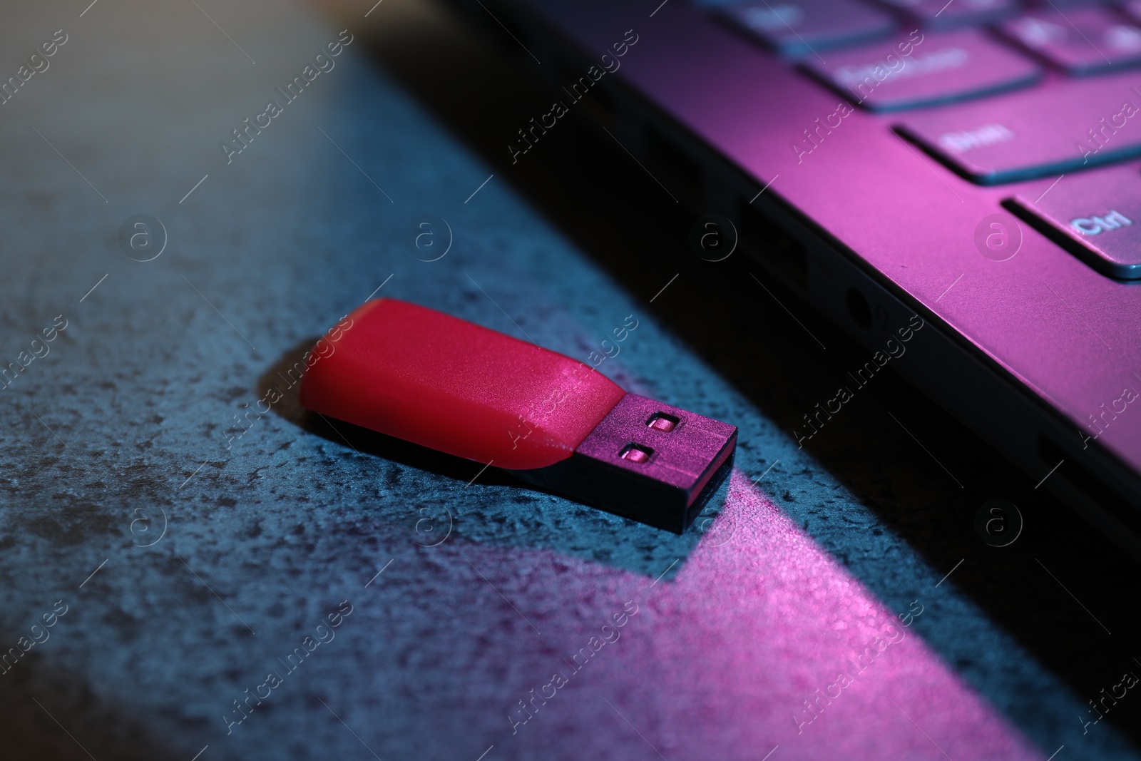 USB flash drive and laptop on dark grey table, closeup Photo of USB flash drive and laptop on dark grey table, closeup