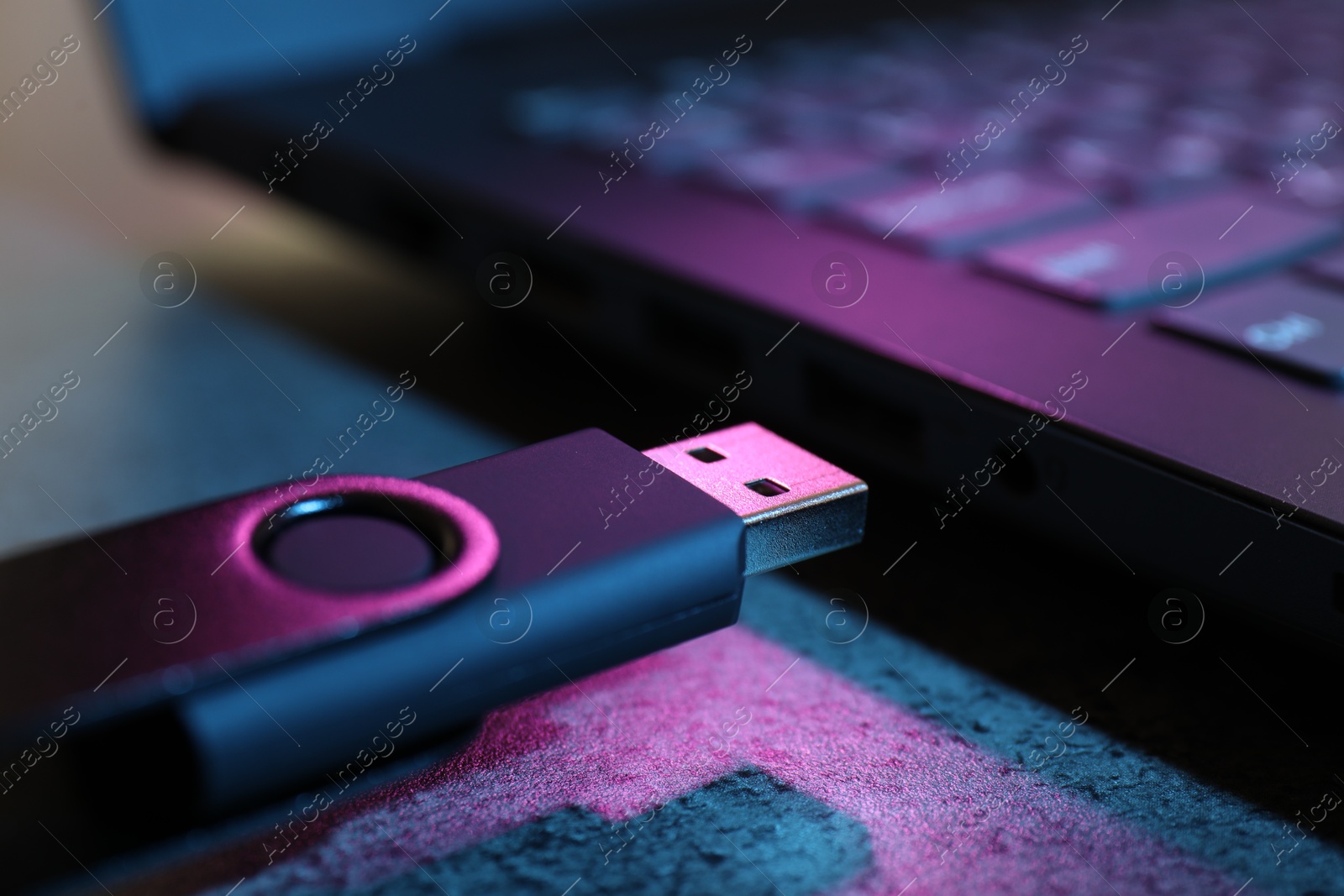USB flash drive and laptop on dark grey table, closeup Photo of USB flash drive and laptop on dark grey table, closeup