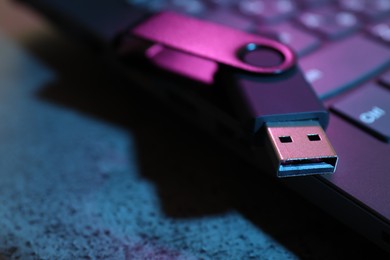 Photo of USB flash drive and laptop on dark grey table, closeup