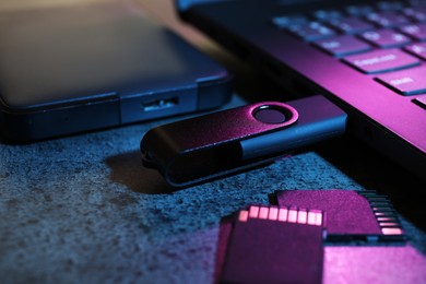 Photo of SD memory cards, USB flash drive, hard disk drive and laptop on dark grey table, closeup