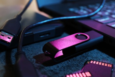Photo of SD memory cards, USB flash drive, hard disk drive with cable and laptop on dark grey table, closeup