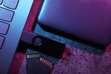 Photo of SD memory cards, USB flash drive, hard disk drive and laptop on dark grey table, flat lay
