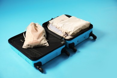 Photo of Open suitcase with packing cubes on light blue background