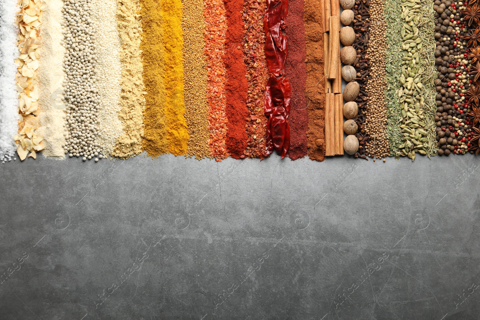 Many different spices on grey table, flat lay. Space for text Photo of Many different spices on grey table, flat lay. Space for text
