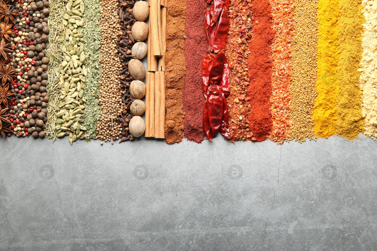 Many different spices on grey table, flat lay. Space for text Photo of Many different spices on grey table, flat lay. Space for text