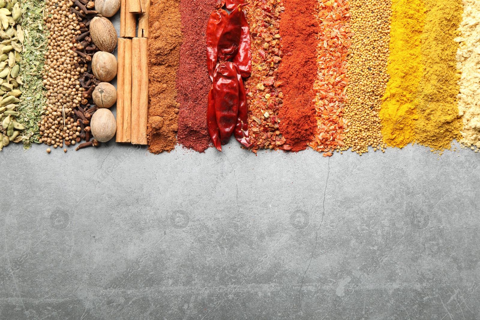 Many different spices on grey table, flat lay. Space for text Photo of Many different spices on grey table, flat lay. Space for text