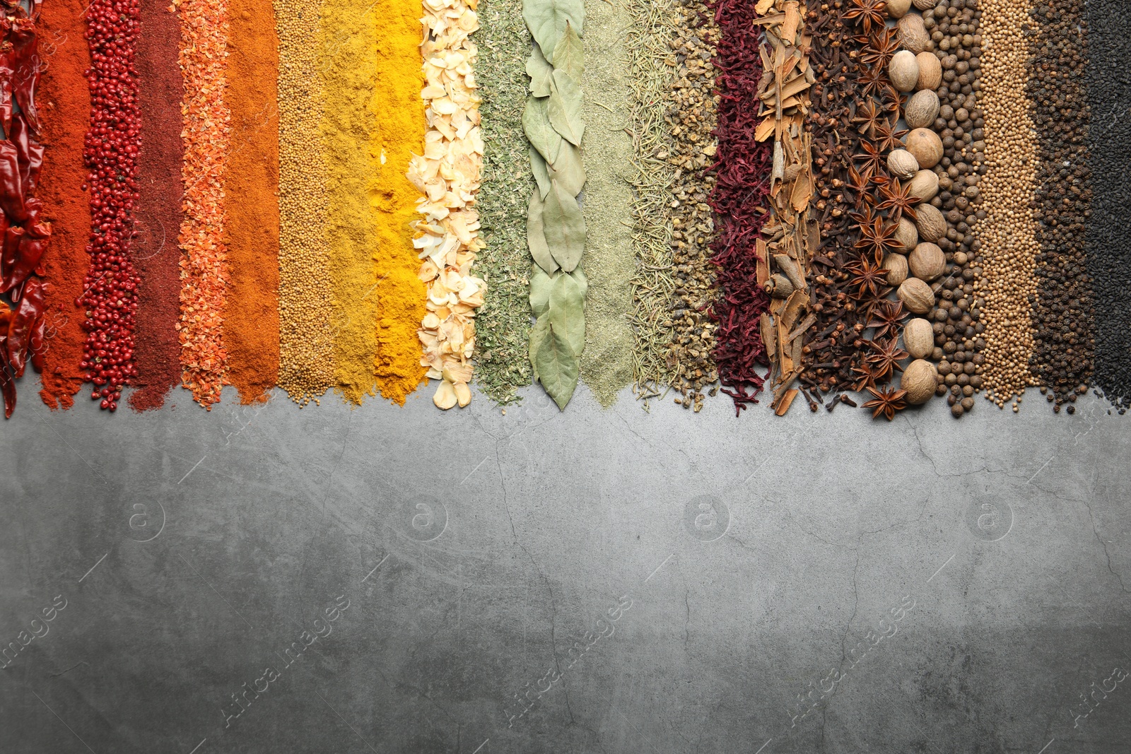 Many different spices on grey table, flat lay. Space for text Photo of Many different spices on grey table, flat lay. Space for text
