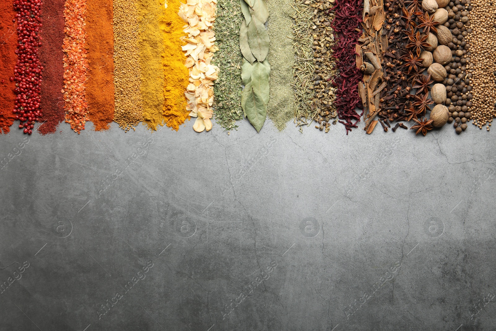 Many different spices on grey table, flat lay. Space for text Photo of Many different spices on grey table, flat lay. Space for text