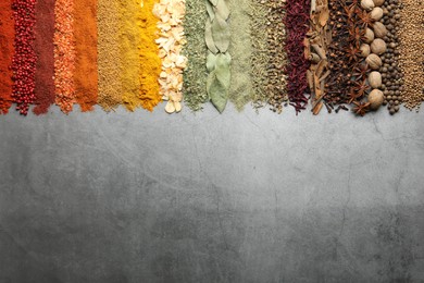 Photo of Many different spices on grey table, flat lay. Space for text