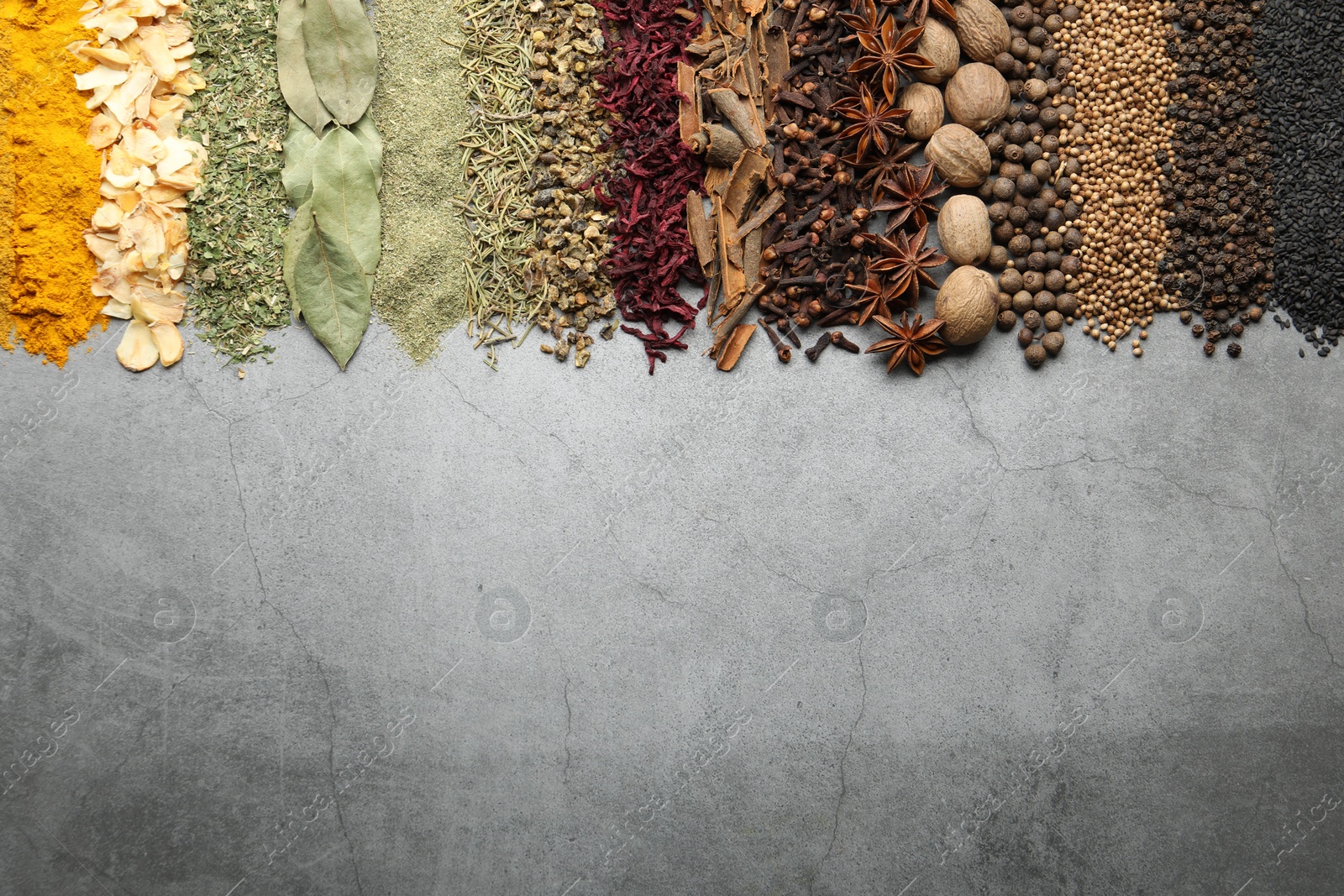 Many different spices on grey table, flat lay. Space for text Photo of Many different spices on grey table, flat lay. Space for text