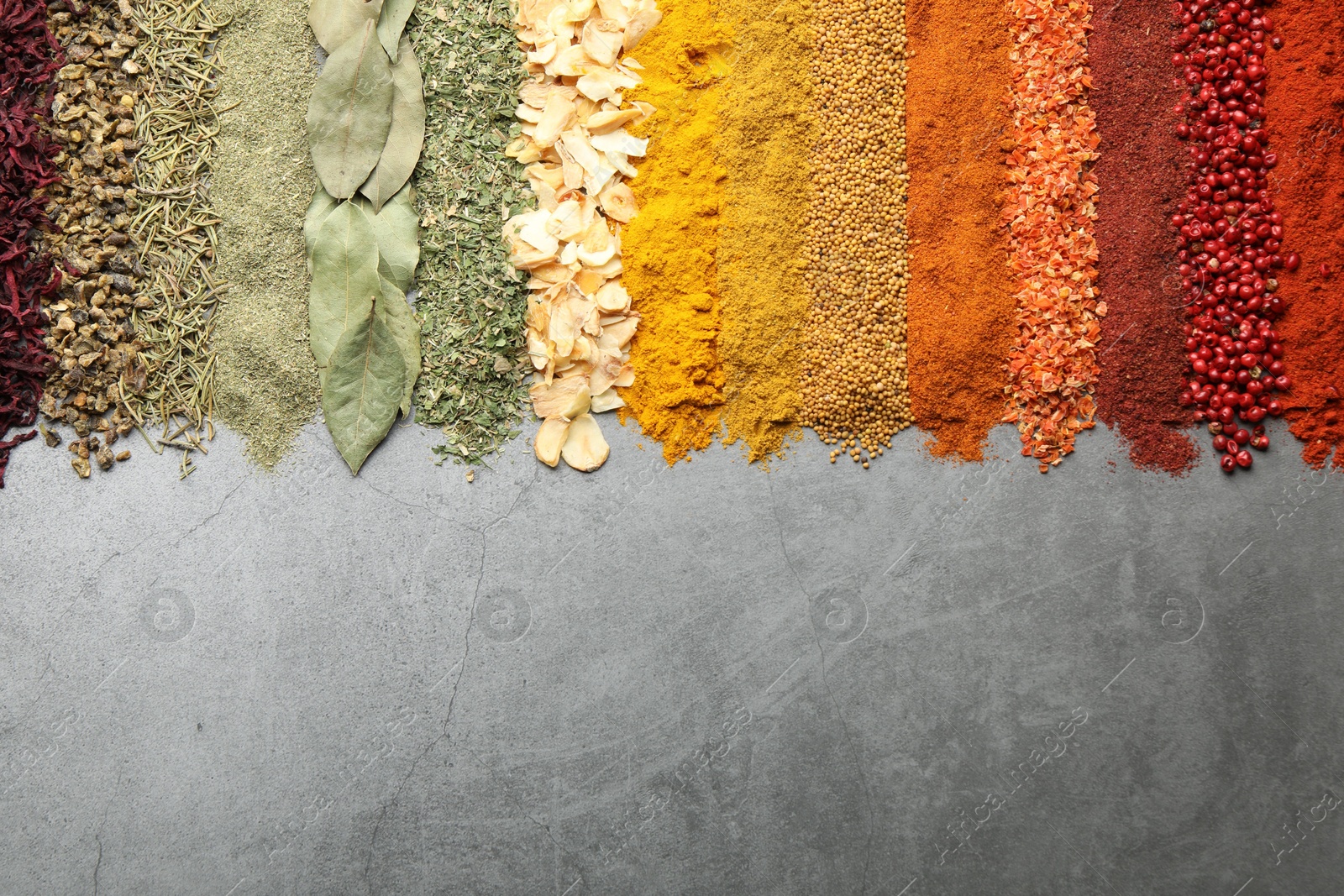 Many different spices on grey table, flat lay. Space for text Photo of Many different spices on grey table, flat lay. Space for text