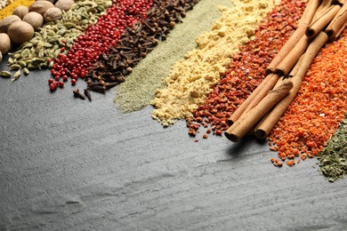 Photo of Many different spices on black table, closeup. Space for text