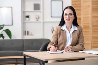 Photo of Professional psychologist taking notes at table in office
