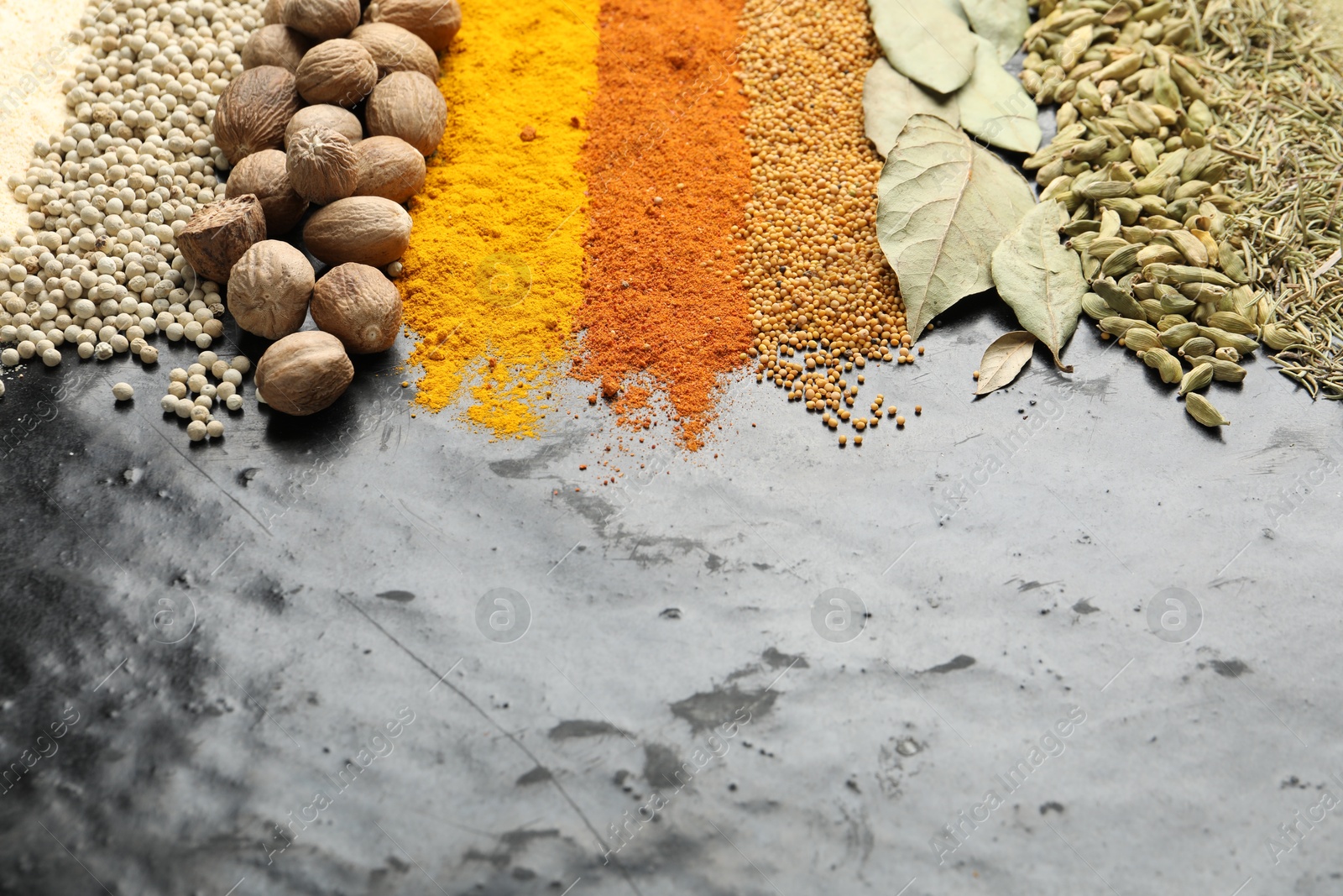 Photo of Many different spices on black table, closeup. Space for text