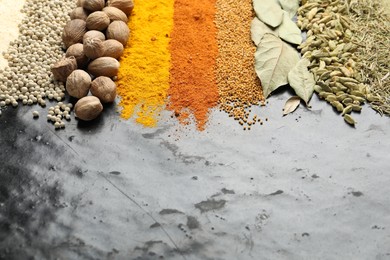 Photo of Many different spices on black table, closeup. Space for text