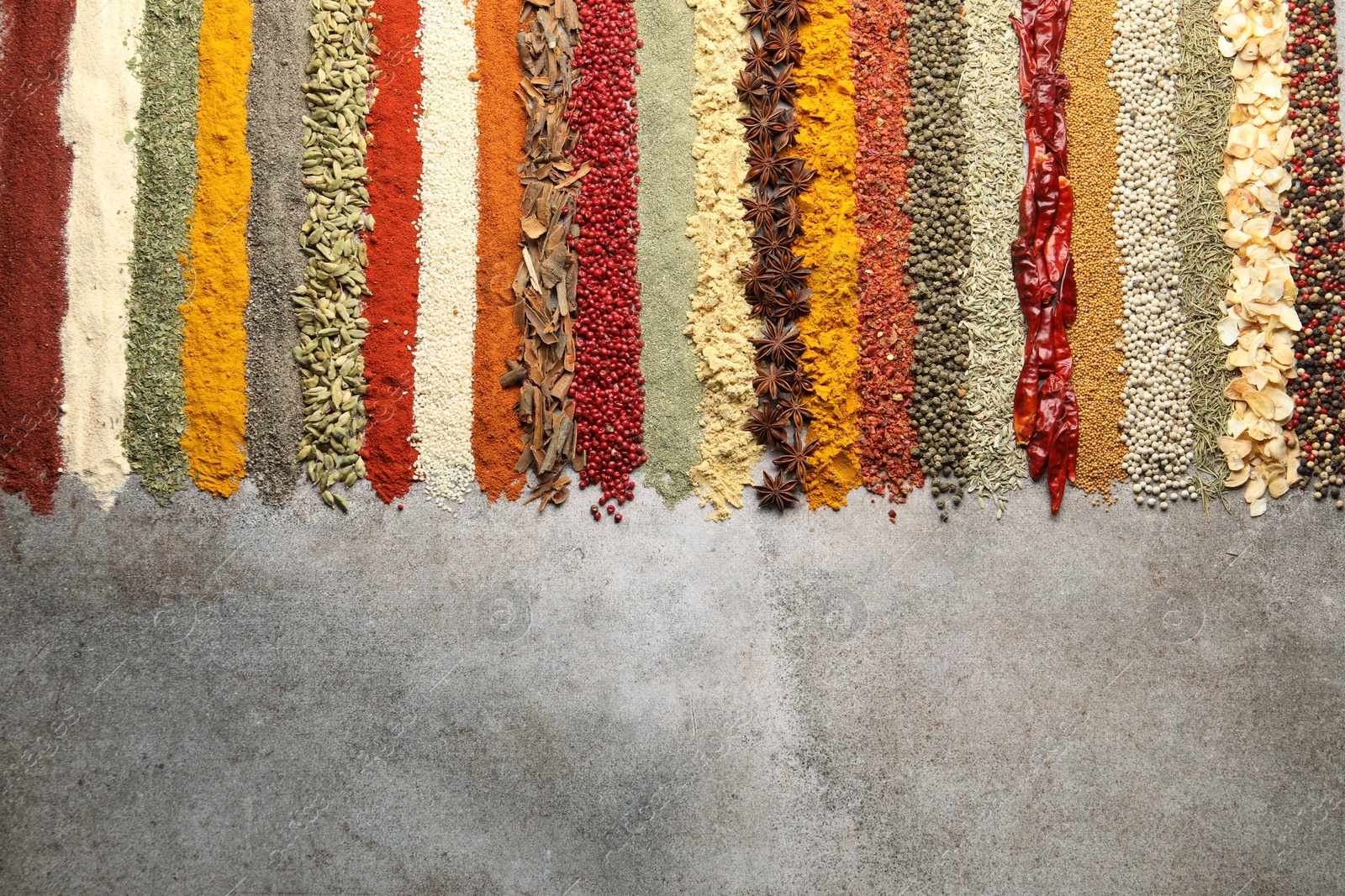 Many different spices on grey table, flat lay. Space for text Photo of Many different spices on grey table, flat lay. Space for text