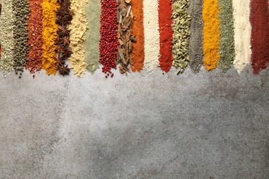 Photo of Many different spices on grey table, flat lay. Space for text