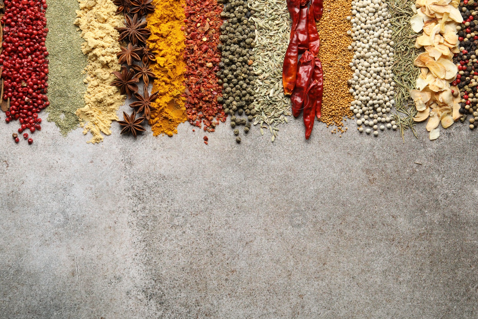 Many different spices on grey table, flat lay. Space for text Photo of Many different spices on grey table, flat lay. Space for text