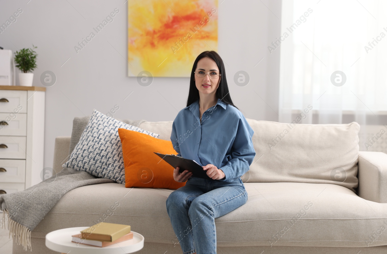 Professional psychologist with clipboard on sofa in office Photo of Professional psychologist with clipboard on sofa in office