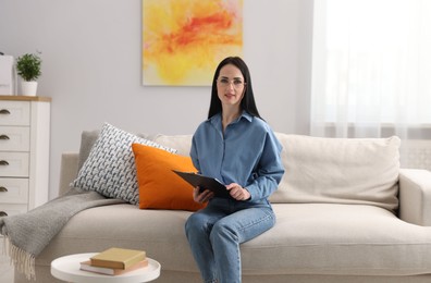 Photo of Professional psychologist with clipboard on sofa in office