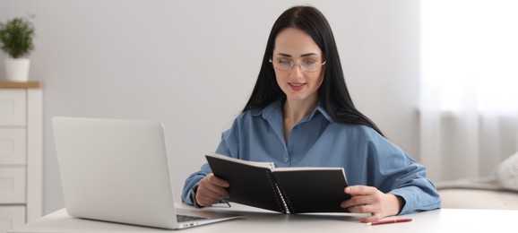 Photo of Professional psychologist with notebook and laptop at table in office