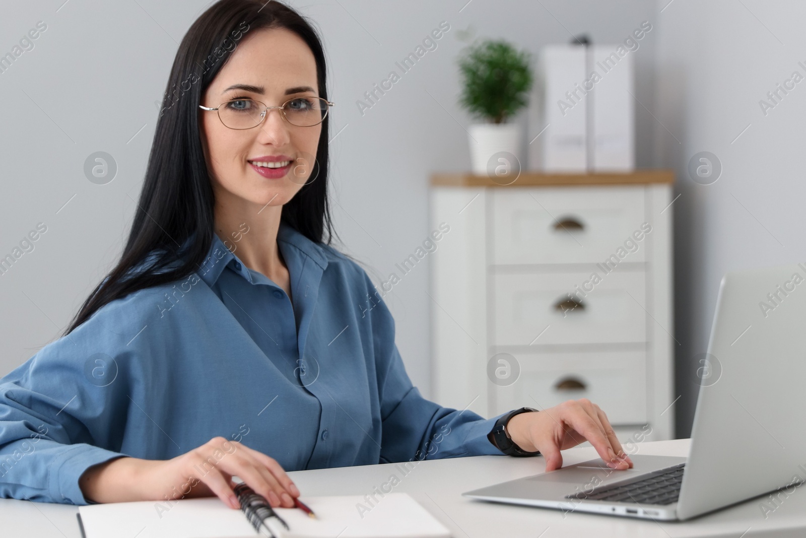 Professional psychologist with laptop, notebook and pen at table in office Photo of Professional psychologist with laptop, notebook and pen at table in office