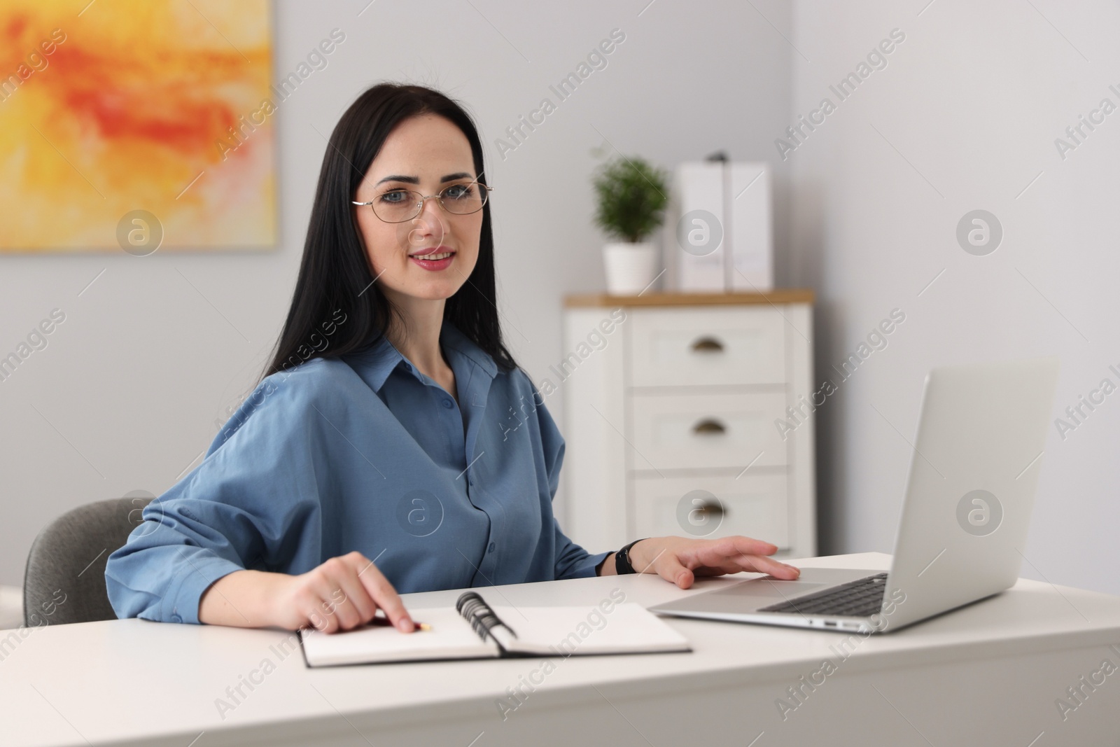 Professional psychologist with laptop, notebook and pen at table in office Photo of Professional psychologist with laptop, notebook and pen at table in office
