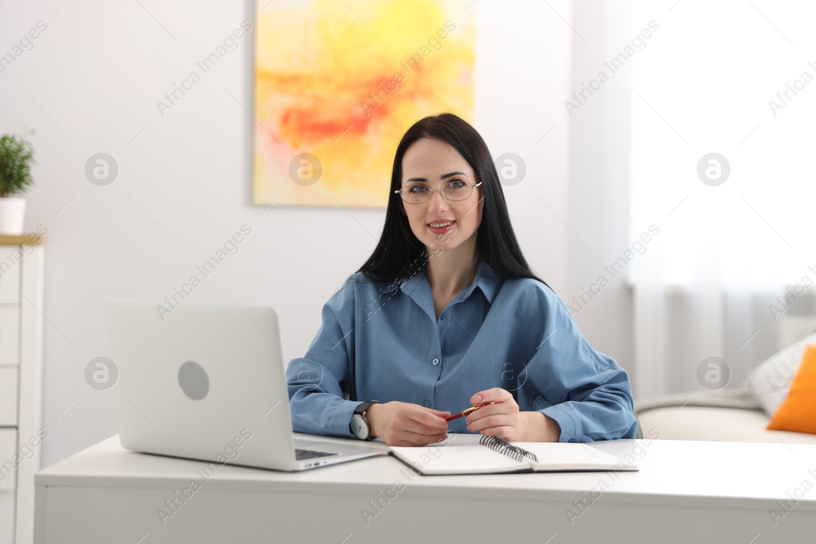 Professional psychologist with laptop, notebook and pen at table in office Photo of Professional psychologist with laptop, notebook and pen at table in office