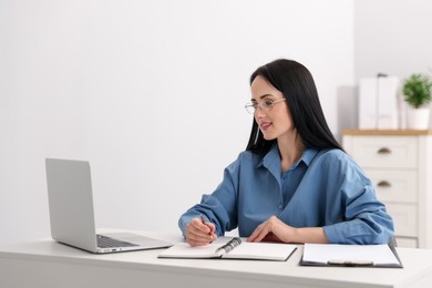 Photo of Professional psychologist working with laptop at table in office