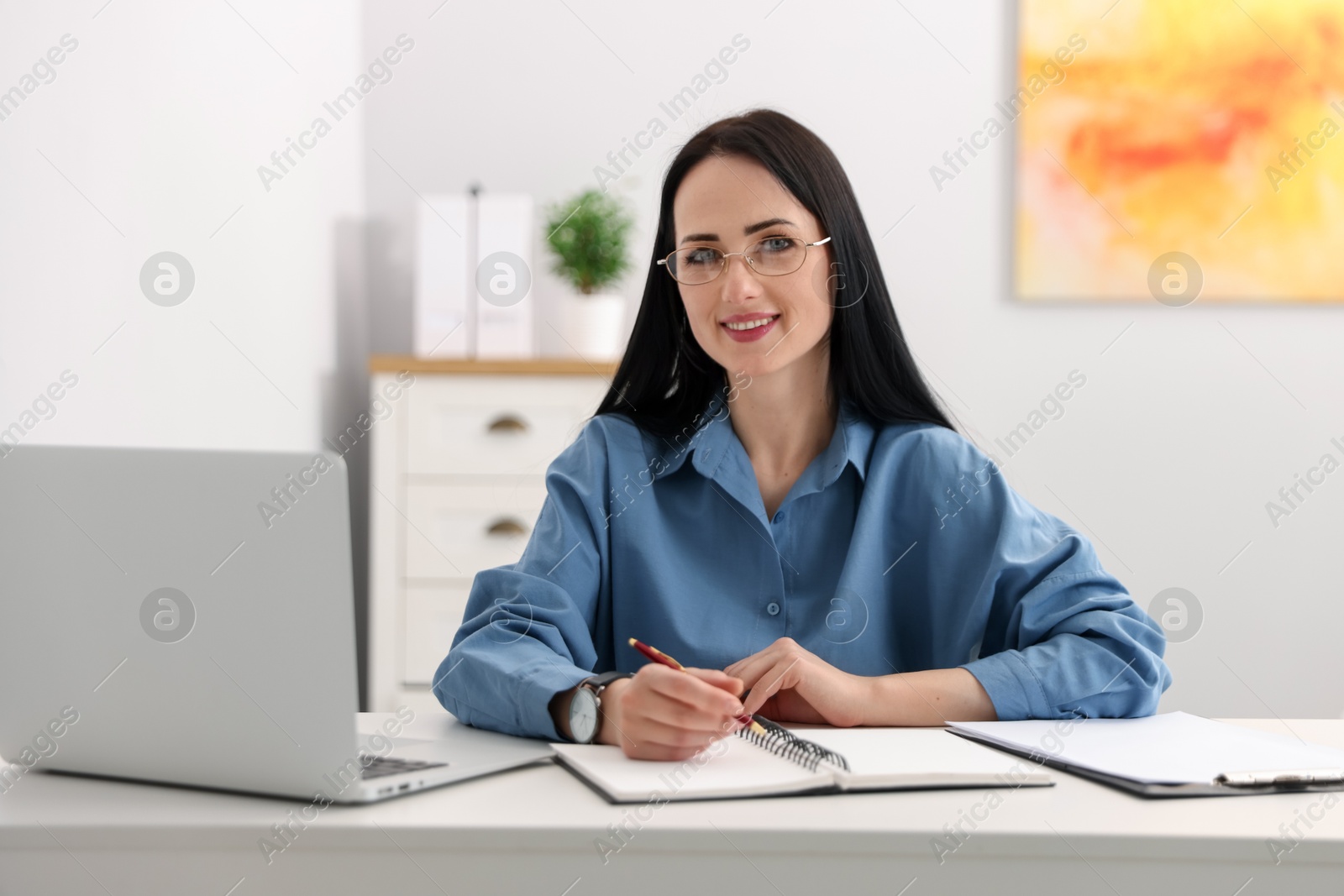 Professional psychologist with laptop, notebook and pen at table in office Photo of Professional psychologist with laptop, notebook and pen at table in office