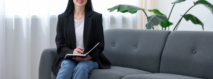Photo of Professional psychologist with notebook and pen in office, closeup. Space for text