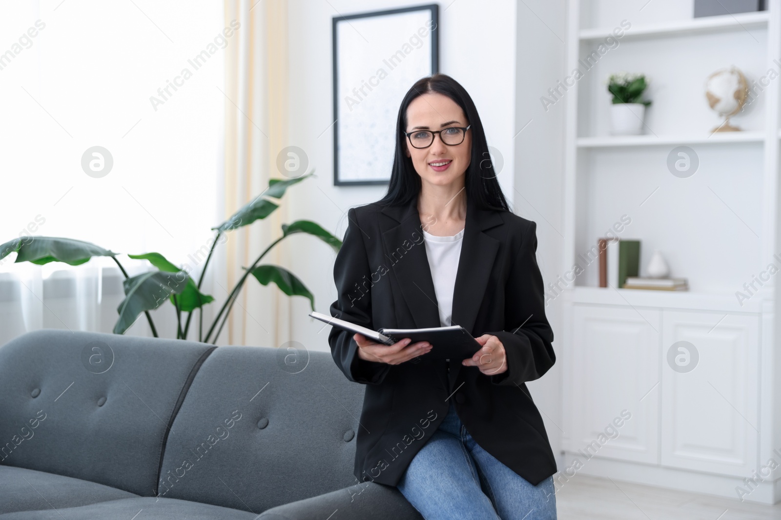 Professional psychologist with notebook on sofa in office Photo of Professional psychologist with notebook on sofa in office