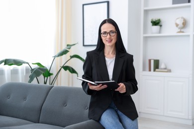 Photo of Professional psychologist with notebook on sofa in office