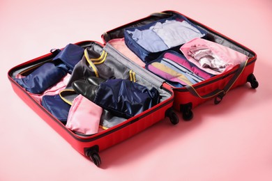 Photo of Open suitcase with packing cubes on pink background