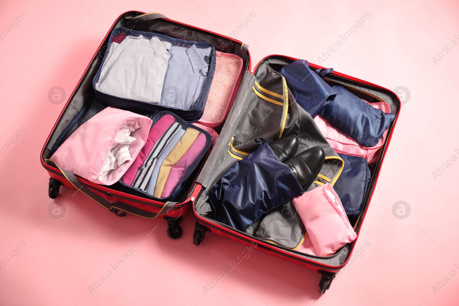 Open suitcase with packing cubes on pink background, above view Photo of Open suitcase with packing cubes on pink background, above view