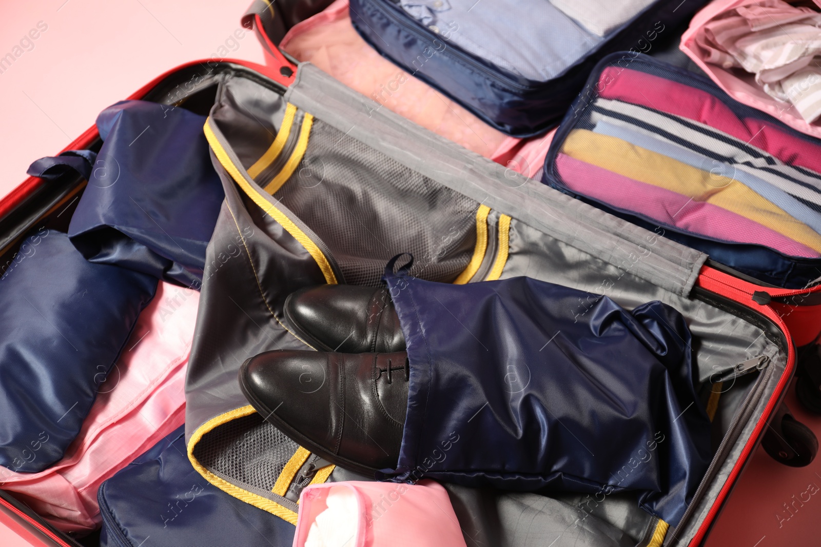 Open suitcase with packing cubes on pink background, closeup Photo of Open suitcase with packing cubes on pink background, closeup