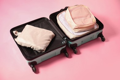 Photo of Open suitcase with packing cubes on pink background