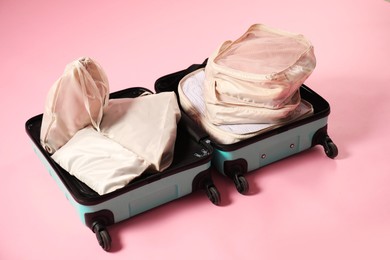 Photo of Open suitcase with packing cubes on pink background
