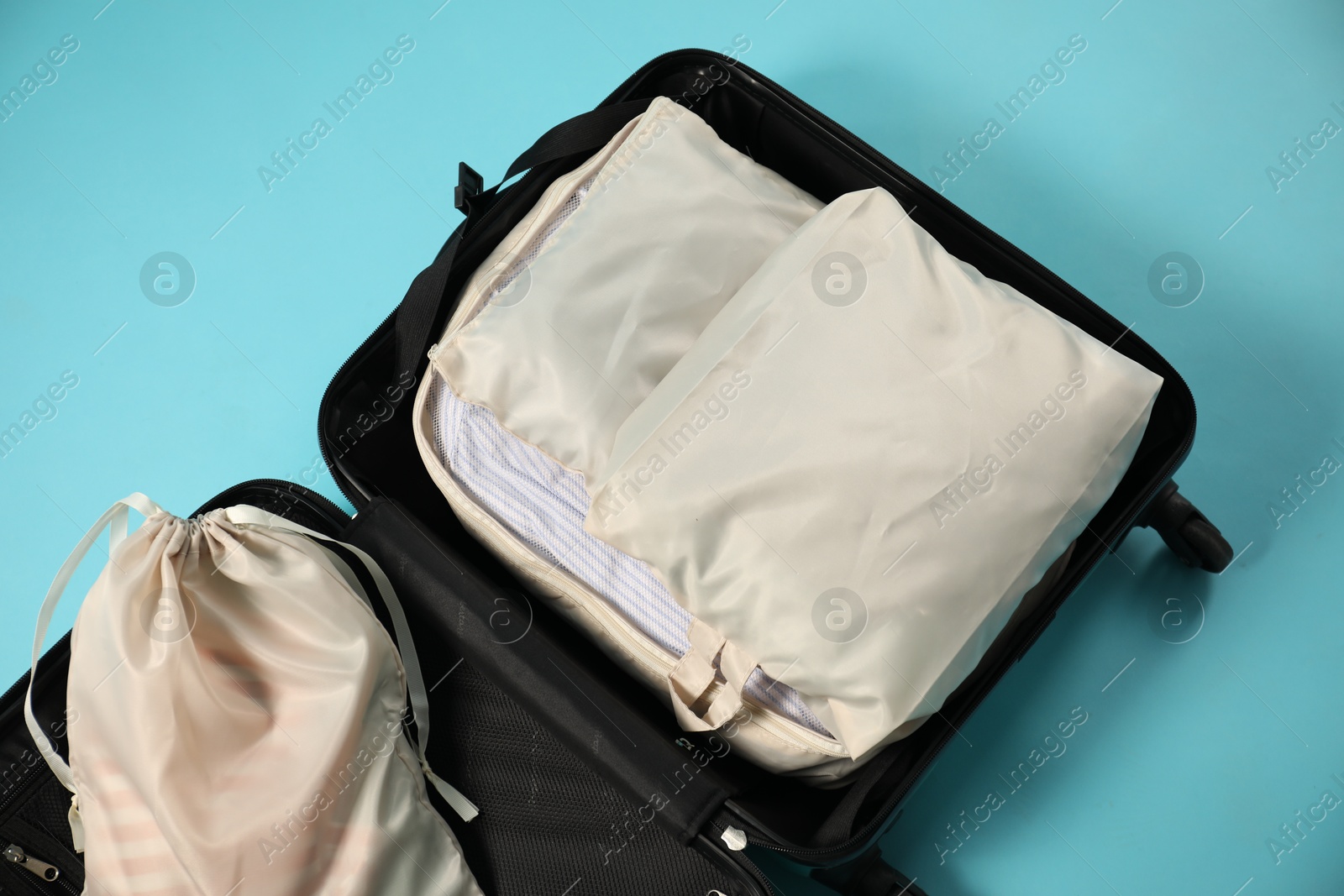 Open suitcase with packing cubes on light blue background, top view Photo of Open suitcase with packing cubes on light blue background, top view