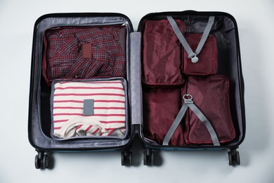 Photo of Open suitcase with packing cubes on white background, top view
