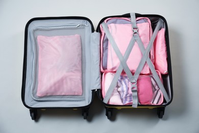 Photo of Open suitcase with packing cubes on light grey background, top view