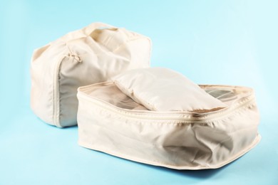 Photo of Packing cubes with clothes on light blue background, closeup