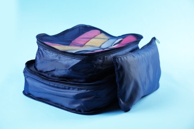 Photo of Packing cubes with clothes on light blue background, closeup