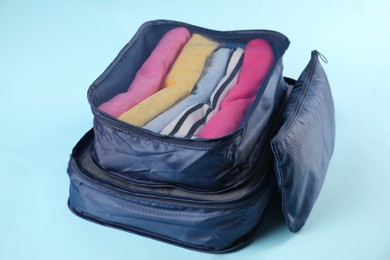 Photo of Packing cubes with clothes on light blue background, closeup