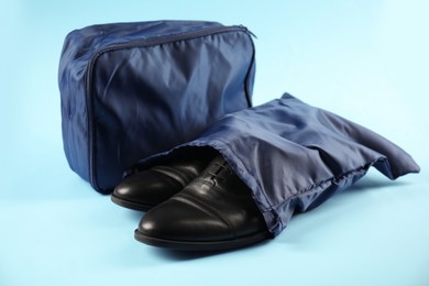 Photo of Packing cubes with clothes and shoes on light blue background, closeup